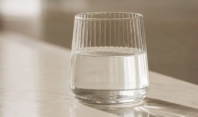 Żebrowana szklanka czystej Kangen Water® na nasłonecznionym blacie